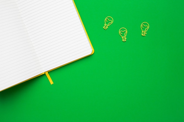 Notebook with blank pages and paperclip light bulb idea on green Premium Photo