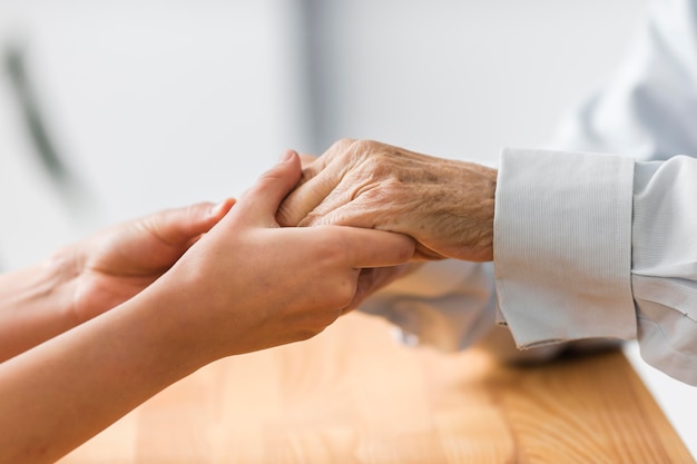 快適さのために年配の男性の手を握っている看護師 無料の写真