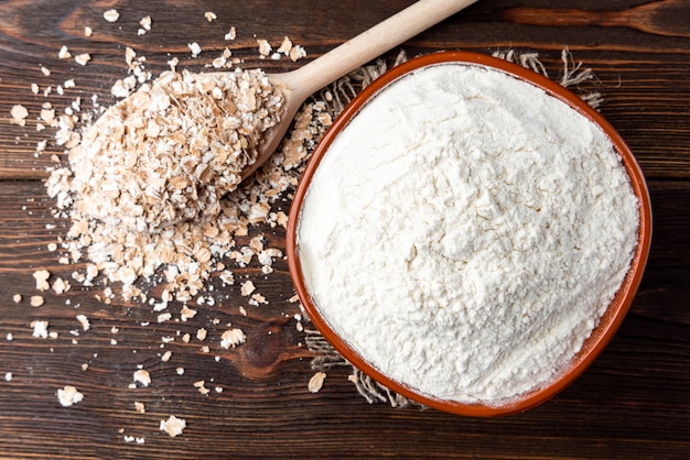 Premium Photo | Oat flakes and flour on dark wood.