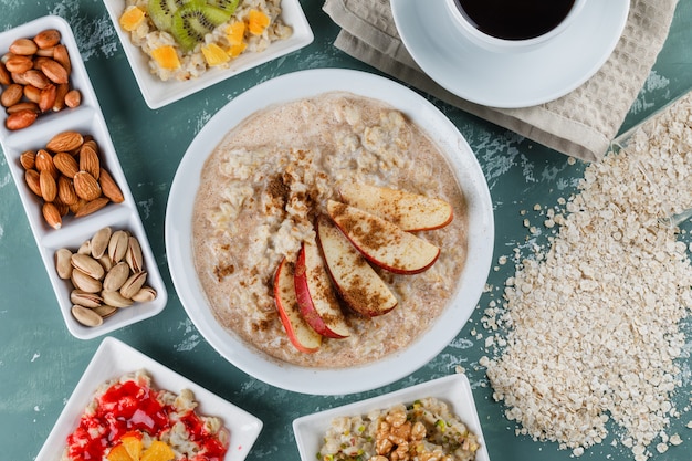 Oatmeal in plates with fruits, jam, nuts, cinnamon, coffee, oat flakes Free Photo