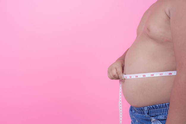 Obese boy who is overweight on a pink background. Free Photo
