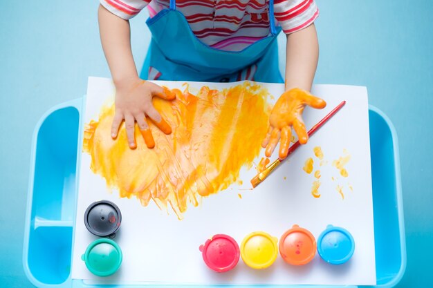 Oddler baby boy child finger painting with hands and watercolors Premium Photo