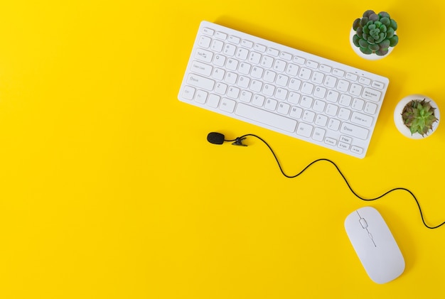 キーボード マウス マイク 植物のオフィスデスクテーブルは 平らな黄色の背景に平面図を配置します リモート作業会議のコンセプト プレミアム写真