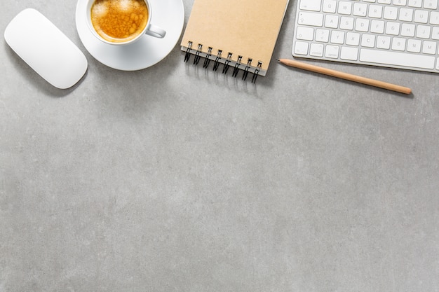 Office table with cup of coffee, keyboard and notepad Free Photo
