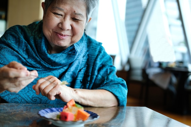 Premium Photo | Old asian elderly senior elder woman eating fruit at  restaurant