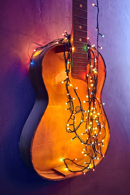 古い壊れたギターには 輝くガーランドが飾られています クリスマスのインテリア 黄色の新年の電球 プレミアム写真