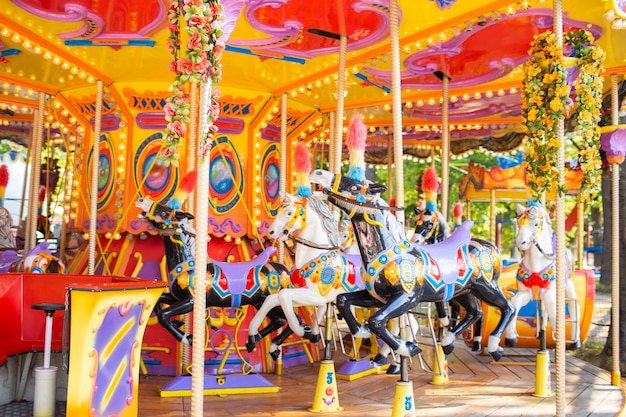 休日の公園で古いフランスのカルーセル 伝統的な見本市会場のビンテージカルーセルに3頭の馬 馬とメリーゴーランド プレミアム写真