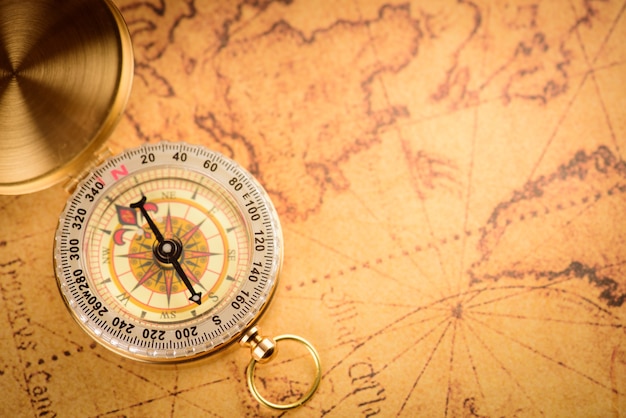 Premium Photo | Old gold vintage compass on vintage map:heading south