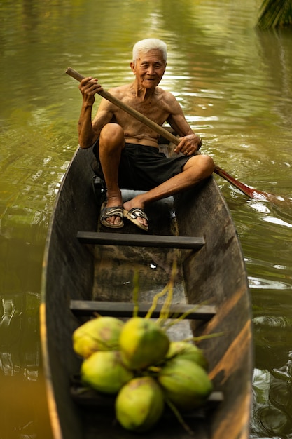Old man collecting coconut by using boat in cococut farm Premium Photo