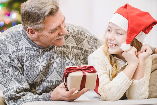 Premium Photo | The old man giving a gift box to a happy granddaughter