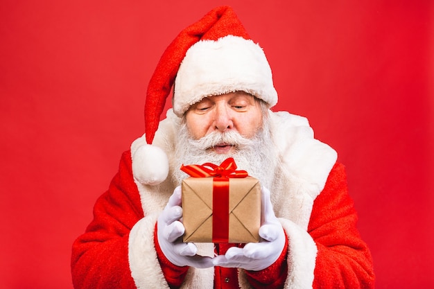 Premium Photo | Old man in santa claus costume holding a present ...