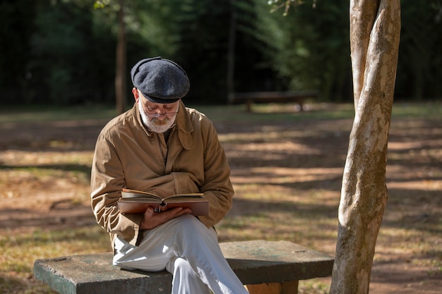 Premium Photo Old Man Sitting On The Bench Reading A Book 0173