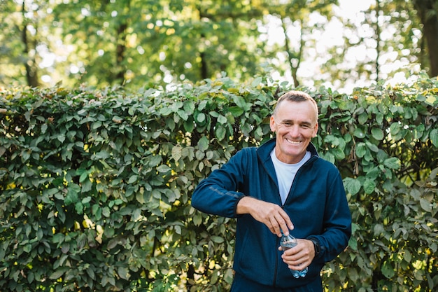 Old man smiling while holding a water bottle in hand Free Photo