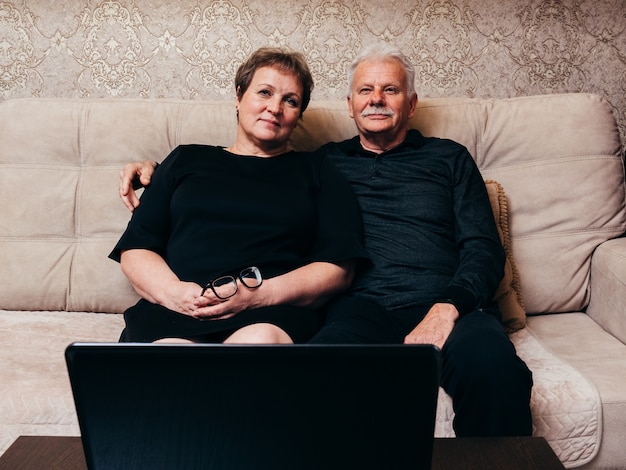 Old man and woman in black clothes are sitting at home in front of a  laptop. | Premium Photo