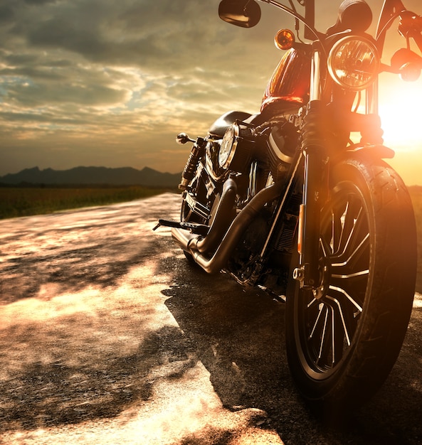 Old retro motorcycle traveling on country road against beautiful light ...