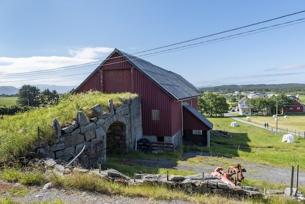Free Photo Old Stone Bridge Connecting To A Red Barn Surrounded By Greenery And Short Trees In Alesund Norway