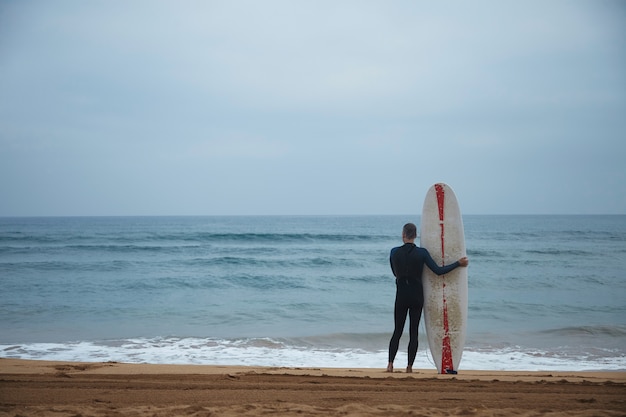 Free Photo | Old surfer with his longboard stays alone on beach in ...