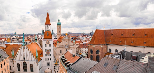 Old town hall surrounded by buildings under a cloudy sky at daytime in munich, germany Free Photo