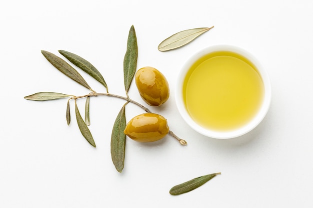 Olive oil saucer with leaves and yellow olives Free Photo