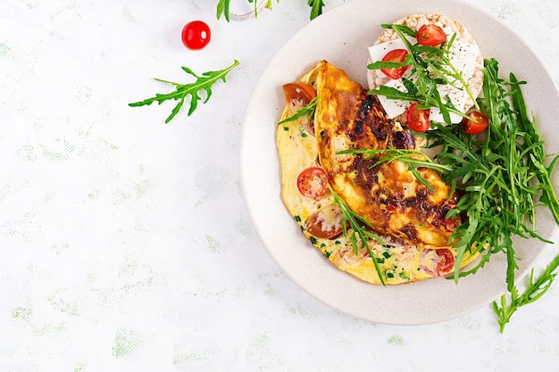 Premium Photo | Omelette with tomatoes, cheese and green herbs on plate ...