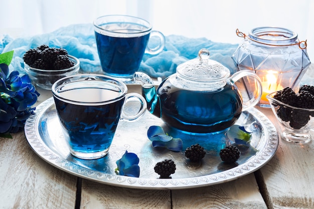 on-a-white-wooden-table-blue-tea-in-transparent-cups-a-blackberry_75514-226.jpg