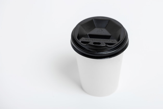 One focused take away white paper cup with black cap presented in front, isolated on simple gray background Premium Photo