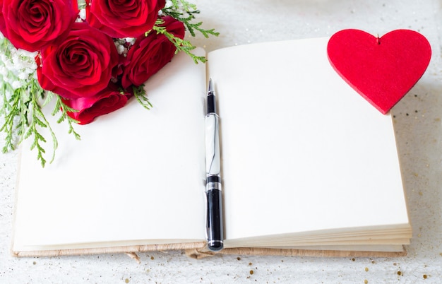 Premium Photo | Open book with blank pages and pen over and red roses and  felt heart background