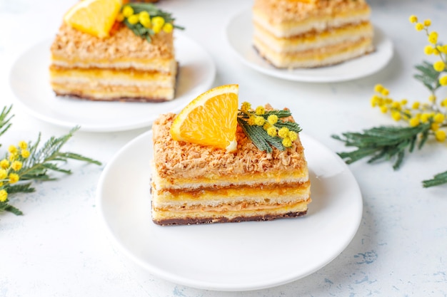 Orange cake decorated with fresh orange slices and mimosa flowers on light Free Photo