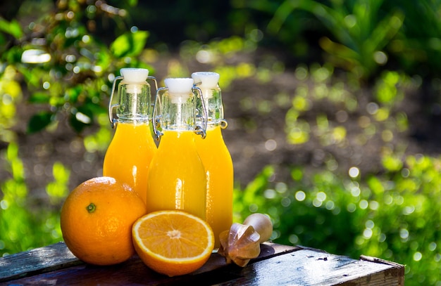 Premium Photo | Orange juice in glass bottles in a summer garden