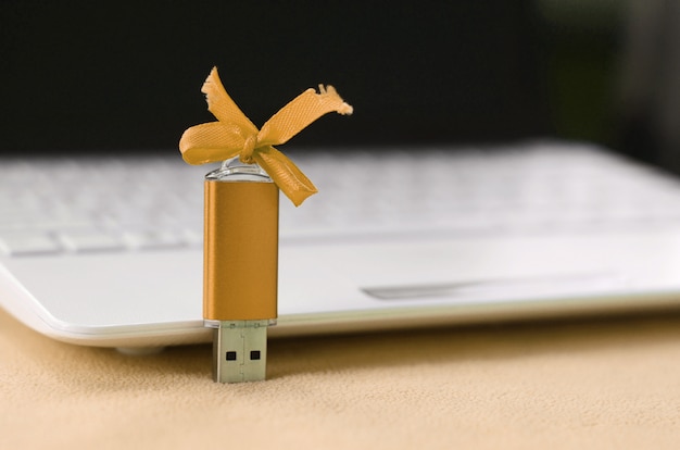 Orange usb flash memory card with a bow lies on blanket Premium Photo