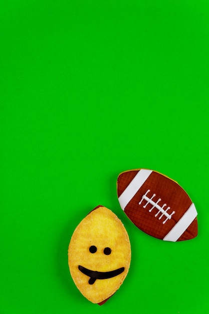 緑の背景に分離されたアメリカンフットボールのボールとして楕円形の変な顔のクッキー 上面図 プレミアム写真