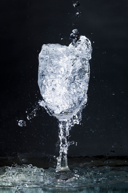 Overflowing water glass on dark background Photo | Free Download