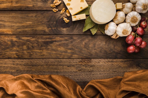 Overhead view of cheese and ingredient with brown cloth over weathered wooden desk Free Photo