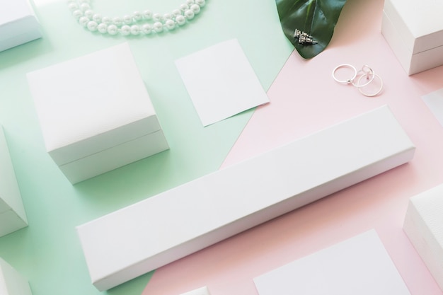 Overhead view of different white boxes on two green and pink paper backdrop Free Photo