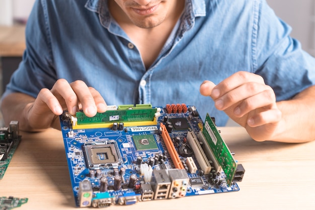Overhead view of it male technician repairing motherboard Free Photo