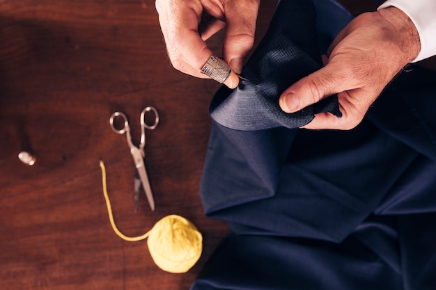 An overhead view of a man's hand sewing fabric with needle Free Photo