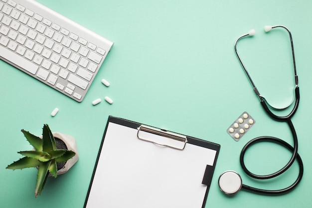 Overhead view of medical desk with succulent plant and wireless keyboard on green surface Free Photo
