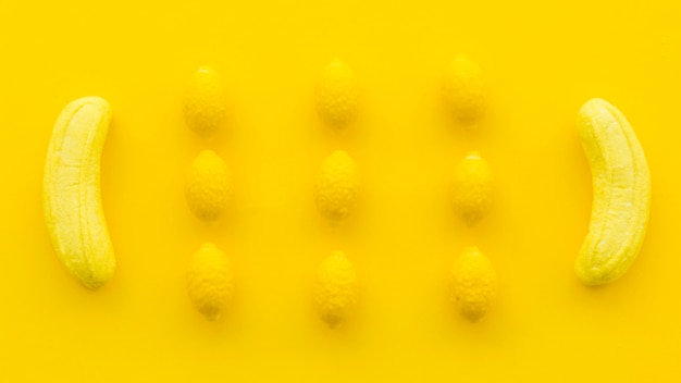 黄色の背景にバナナとレモンキャンディのオーバーヘッドビュー 無料の写真