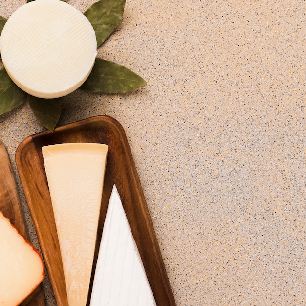 Overhead view of white cheese; parmesan cheese and spanish manchego cheese arranged over smooth backdrop Free Photo