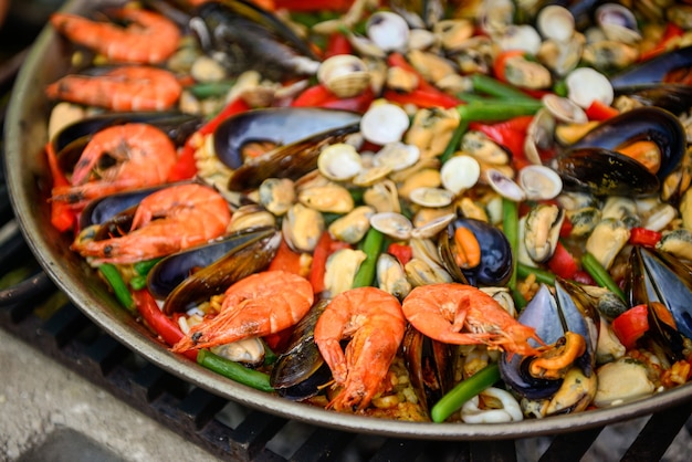 Premium Photo | Paella being prepared on improvised stove.