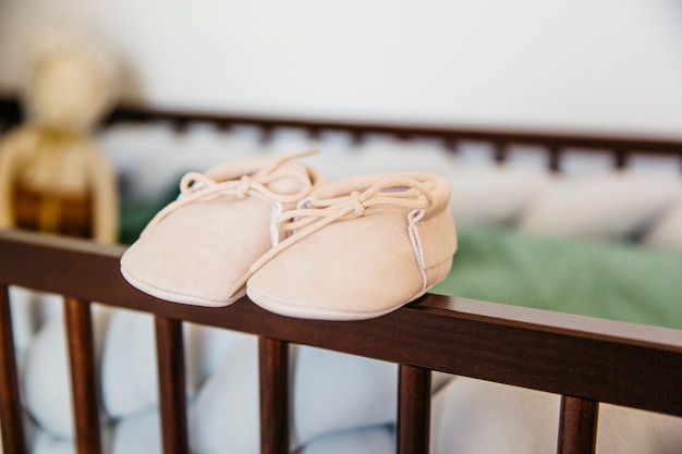 Pair Of Baby Shoes On The Edge Of Wooden Crib Free Photo