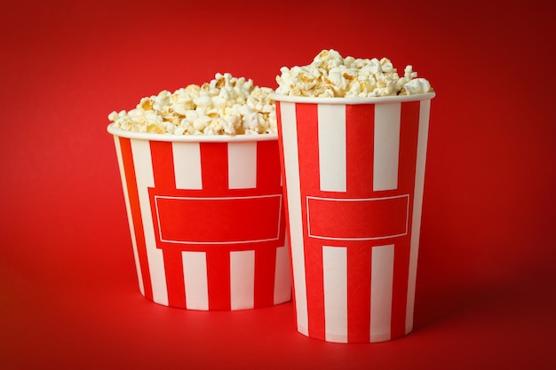 Premium Photo | Paper cups with popcorn on red background.