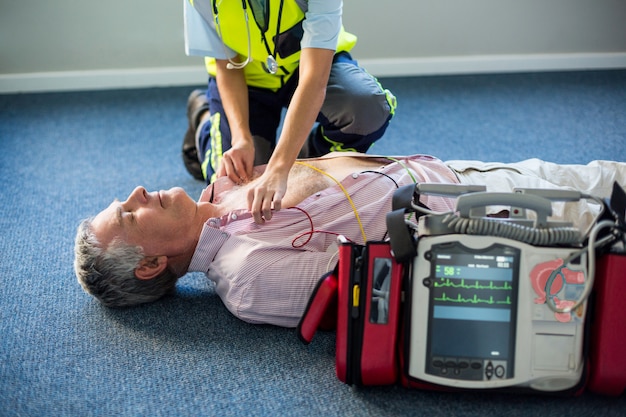 Premium Photo | Paramedic using an external defibrillator on an ...