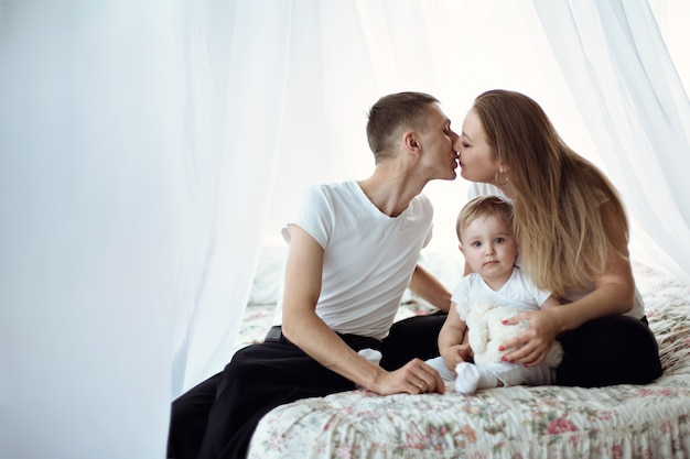 Premium Photo | Parents kissing with their baby in the middle