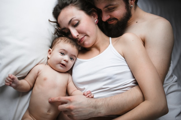 Premium Photo Parents Lying On A Bed With Their Baby