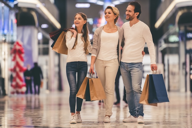 Parents and their daughter are holding shopping bags. Premium Photo