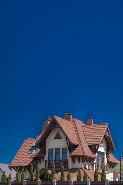 空の瓦屋根の下にあるモダンなレンガ造りの家の一部 バルコニー付きのコテージ 木造住宅 自然に生きる 天然石の仕上げ プレミアム写真