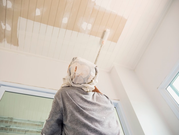 Partial Focus Photo Of A Man Is Painting Ceiling Using Roller
