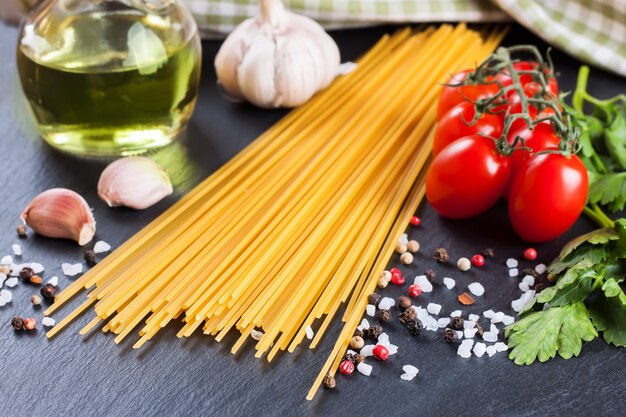 Premium Photo | Pasta ingridients and spice on black slate surface.