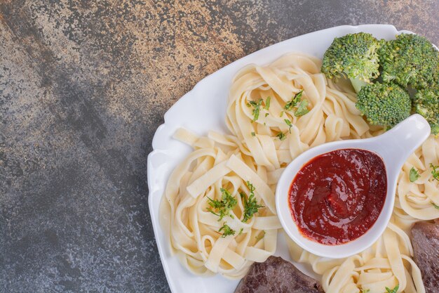 グリーンとトマトペーストのパスタ 白いプレートに肉 無料の写真